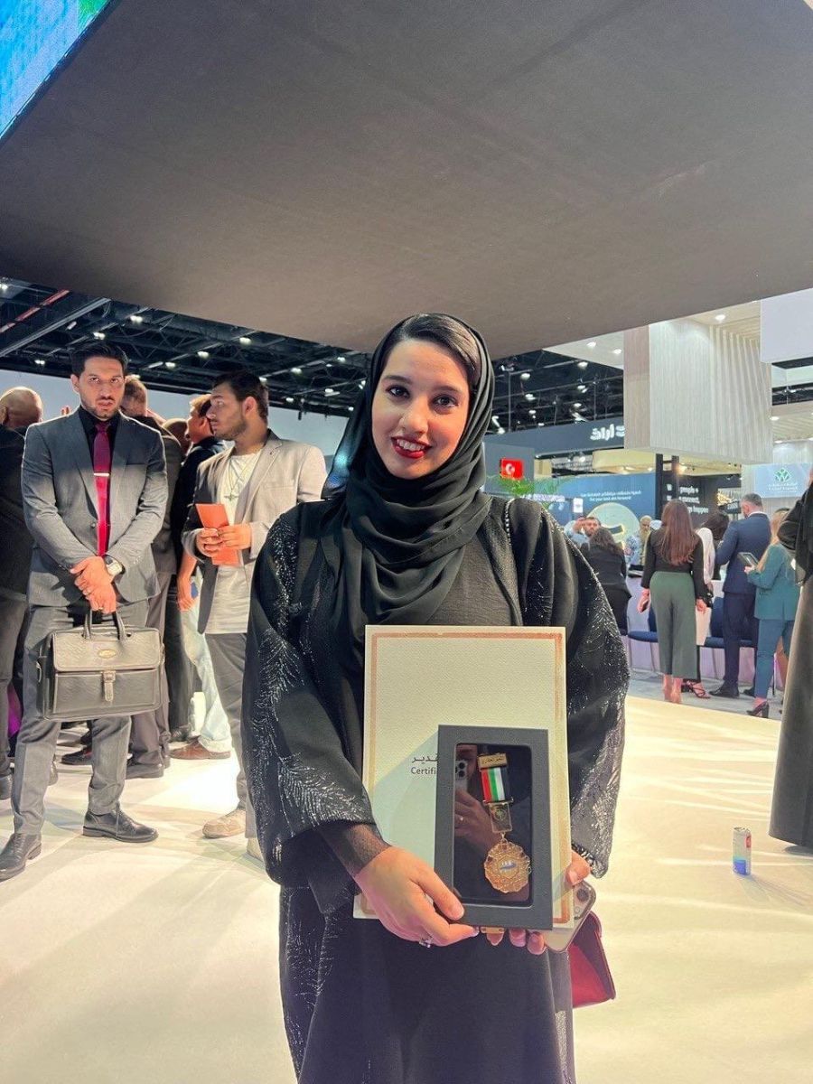 Kolsoum Al Bastaki holding a recognition medal and certificate